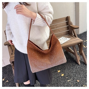 Detail of a brown suede shoulder bag with sparkling rhinestones worn by a model