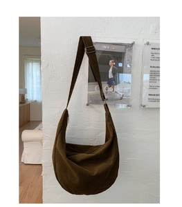 Detailed close-up of dark brown canvas hobo bag texture and adjustable metal buckle strap