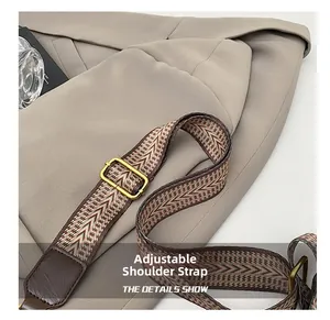 Close-up of adjustable woven shoulder strap with retro gold buckle on a brown dumpling bag