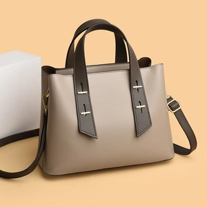 Close-up of a high-quality tote bag with golden cross metal buckle and leather strap