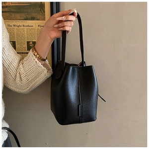 Detail of black lychee grain leather bucket bag with premium stitching held by a model