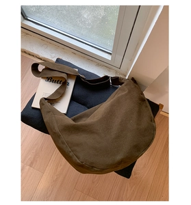 Detail of dark brown canvas dumpling bag with adjustable shoulder strap and silver buckle