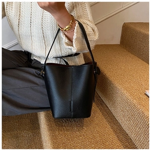 Detail of black lychee grain leather bucket bag with gold hardware and red lining