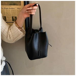 Detail of black pebbled leather bucket bag with top handle and vintage aesthetic
