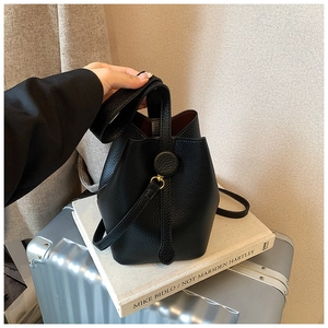 Detail of a black pebble leather bucket bag showing the texture and golden metal ring