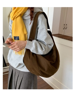 Close-up of brown canvas hobo bag with adjustable wide strap and metal hardware detail
