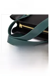 Detail of green handle stitching and gold zipper on black lychee leather tote bag