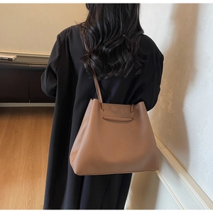 Detailed view of a brown pebbled leather tote bag with drawstring details and slim shoulder strap