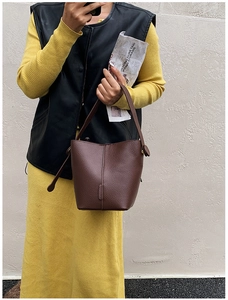 Detail of a brown lychee pattern leather bucket bag with retro round buckle detail