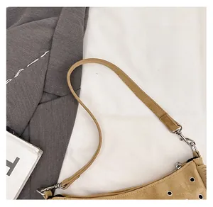 Détail de la bandoulière en daim camel avec crochet argenté sur un sac selle