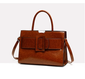 Close-up of vintage brown crossbody bag featuring glossy leather and metallic buckle detail