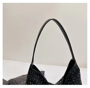 Close-up of stylish black underarm bag with silver rhinestone studs and a smooth leather handle