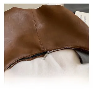 Gros plan d'un sac dumpling en cuir marron avec fermeture éclair argentée et coutures