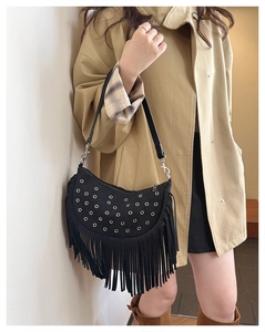 Detail of black suede hobo bag with silver eyelets and long decorative fringes