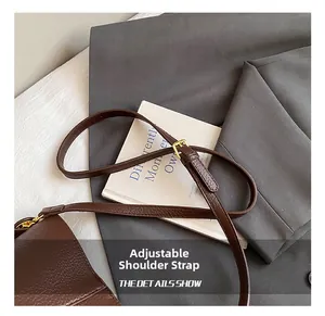 Detail of adjustable shoulder strap with golden buckle on dark brown leather bag