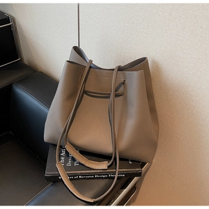 Detail of grey lychee textured leather tote bag on a sofa showing material and strap