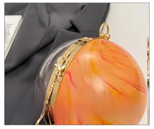Gros plan sur le sac de soirée sphérique en acrylique avec détails dorés et texture marbrée