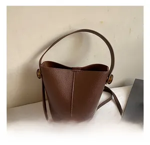 Detail view of brown textured leather bucket bag with top handle and shoulder strap