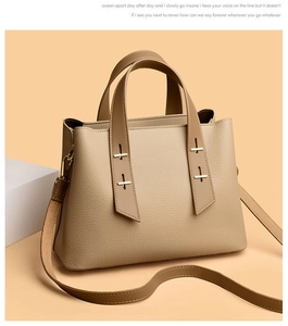 Close-up of beige tote bag with litchi grain texture and golden metal cross hardware