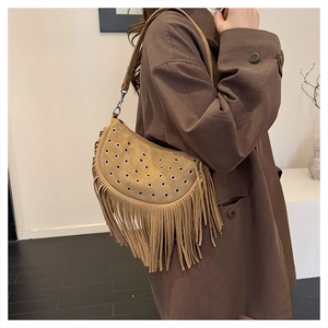 Detail of khaki suede half-moon bag with long tassels and adjustable strap on a model
