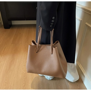 Detailed shot of warm brown lychee grain leather texture on a minimalist tote bag