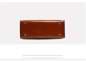 Detail view of large tote bag bottom with four silver protective metal studs and brown leather