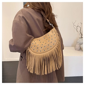 Détail du sac bohème en daim camel avec œillets métalliques et longues franges