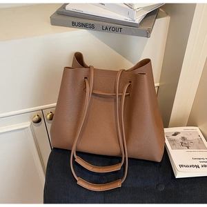 Detailed macro view of brown lychee grain leather texture and drawstring on a tote bag