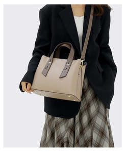 Detailed view of cream leather tote bag with brown straps styled on a fashion model
