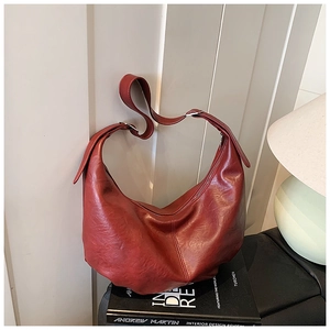 Détail du sac hobo en cuir bordeaux montrant la texture cirée brillante et la bandoulière