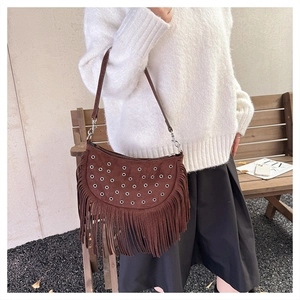 Detail of coffee brown suede fringe bag with metal eyelets in a street style setting