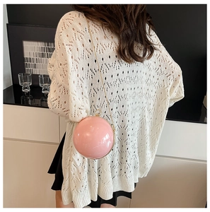 Détail d'un sac de soirée sphérique en acrylique rose vif avec chaîne dorée sur mannequin
