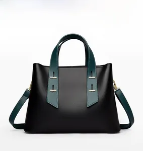 Close-up of black lychee leather tote with green straps and gold stud hardware details