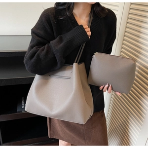 Elephant gray lychee leather tote bag and pouch set worn by model with shoulder strap