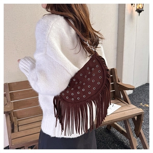 Detail of brown suede crescent bag with silver eyelets and long bohemian fringe tassels