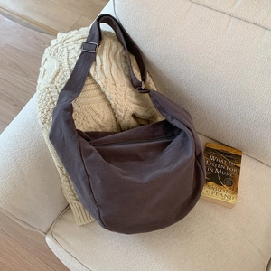 Minimalist dark grey large canvas dumpling shoulder bag with adjustable strap on sofa
