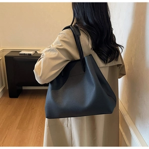 Close-up of black litchi pattern leather tote bag with long handles on shoulder