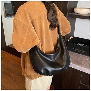 Détail d'un grand sac hobo noir en simili cuir montrant la texture souple et la fermeture éclair