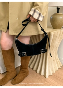 Close-up of black suede crescent bag with silver buckles and retro hardware detail