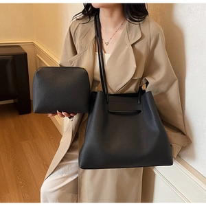 Close-up of black litchi pattern leather tote bag with matching zippered pouch detail