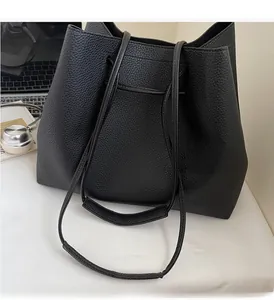 Large black leather tote bag with dual straps shown in a modern office desk setting
