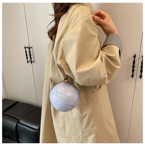 Détail du sac boule en acrylique à motif marbre avec chaîne dorée et cadre en métal
