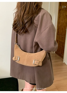 Detail of camel crescent shoulder bag with silver buckles on suede-like fabric texture