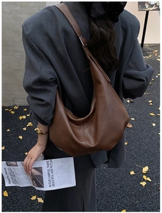 Détail d'un grand sac croissant marron foncé avec une texture en cuir rétro élégante