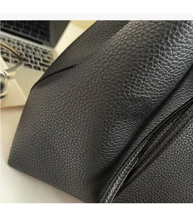 Close-up of premium black lychee leather texture on a spacious commuter tote bag