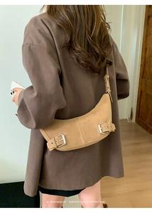 Detailed close-up of a khaki crescent shoulder bag with vintage silver buckles and matte suede
