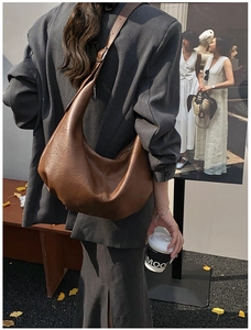 Détail macro du sac hobo en cuir marron foncé avec texture mate et coutures de précision