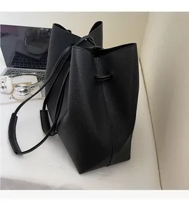 Detailed view of black pebble leather texture and drawstring closure on a bucket bag