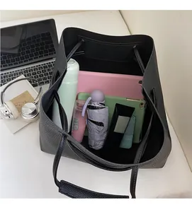 Top view showing the spacious interior of a black lychee leather tote with tablets and umbrella
