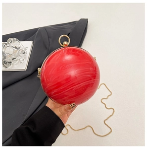 Détail de la pochette sphérique en acrylique rouge marbré avec poignée en métal doré
